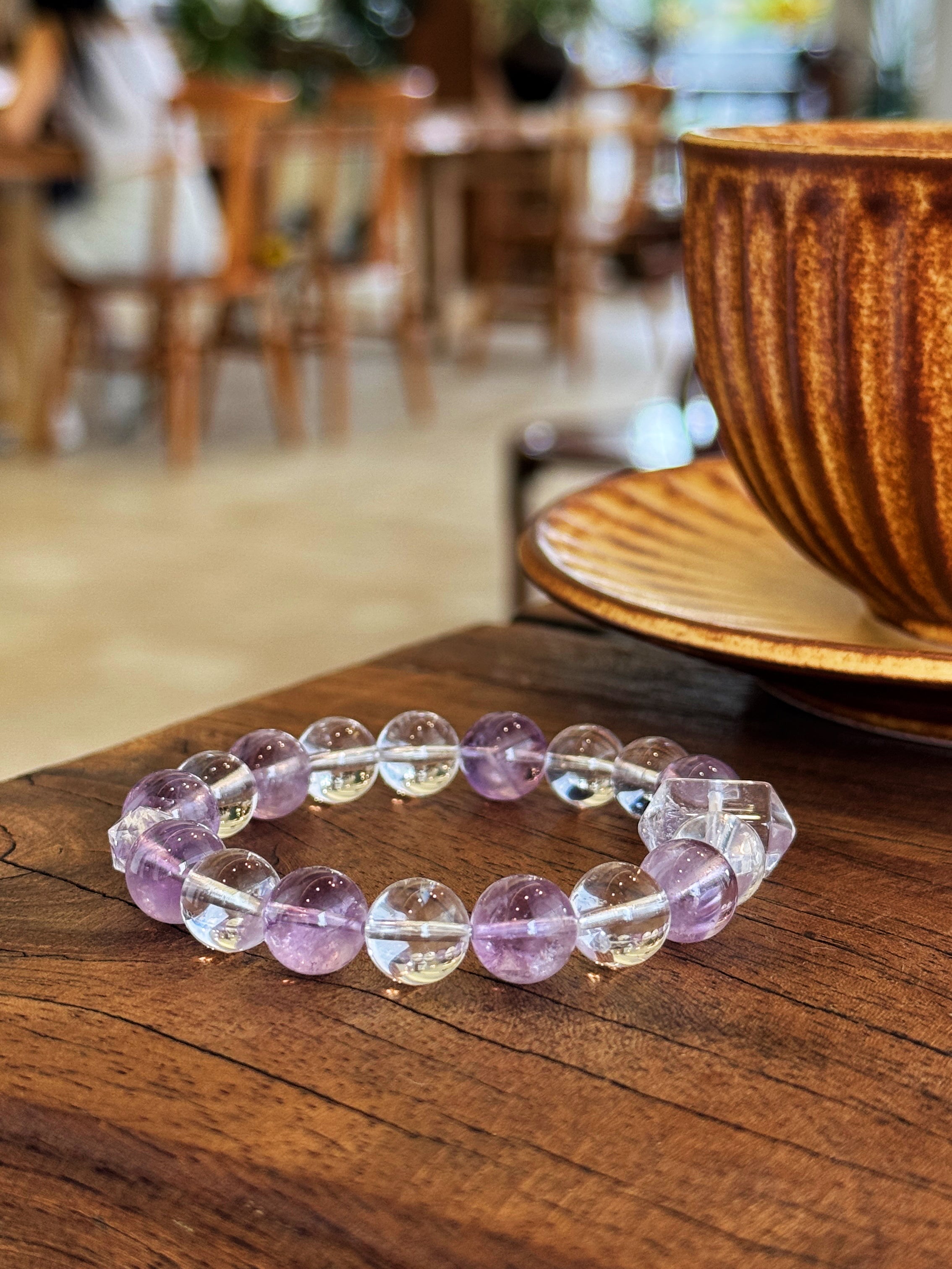 Natural Amethyst and Clear Quartz crystal bracelet on a wooden table in a coffee shop.