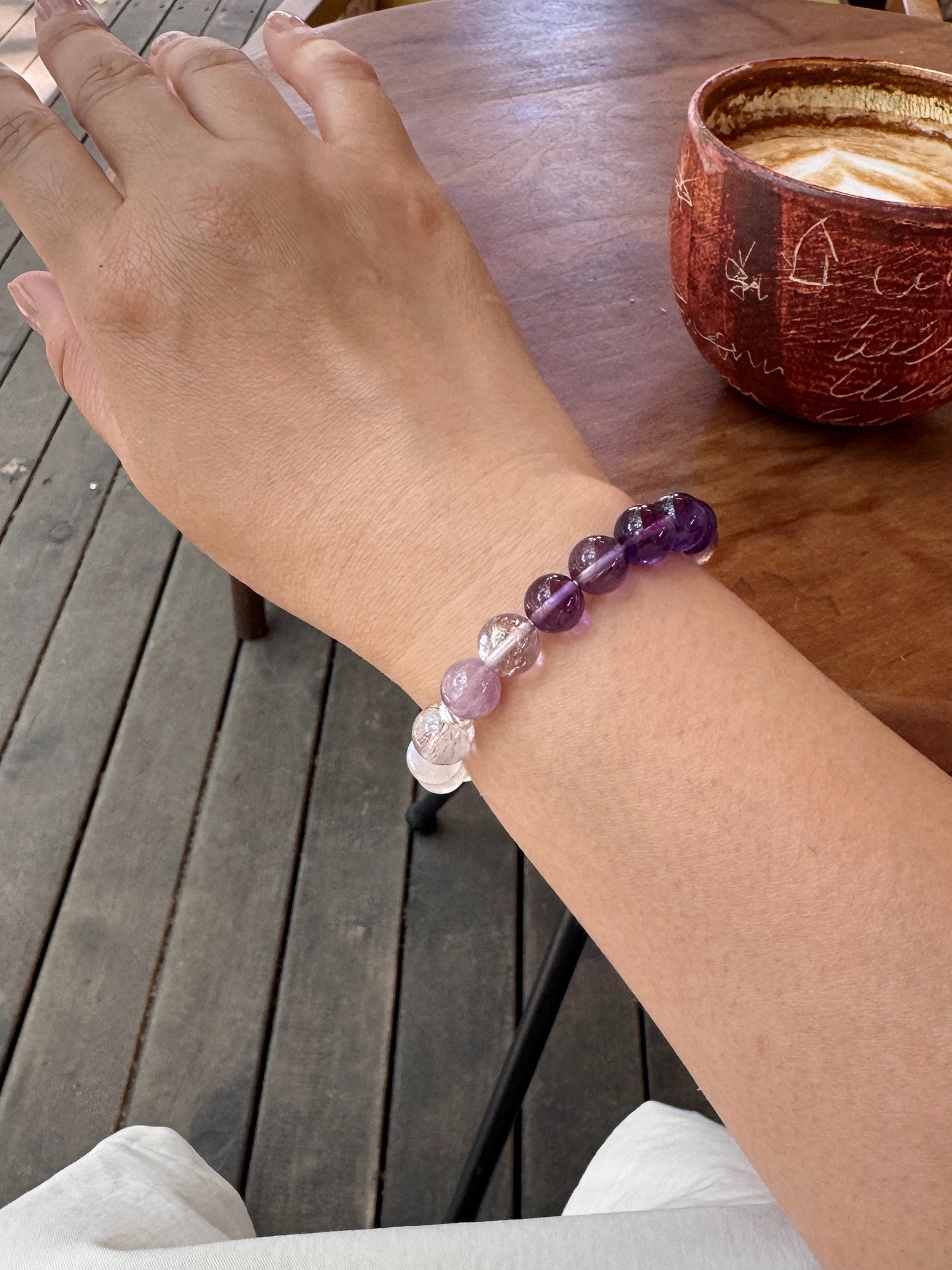 Amethyst, purple titanium quartz, and moonstone bracelet worn on wrist close-up showing layered violet crystal tones