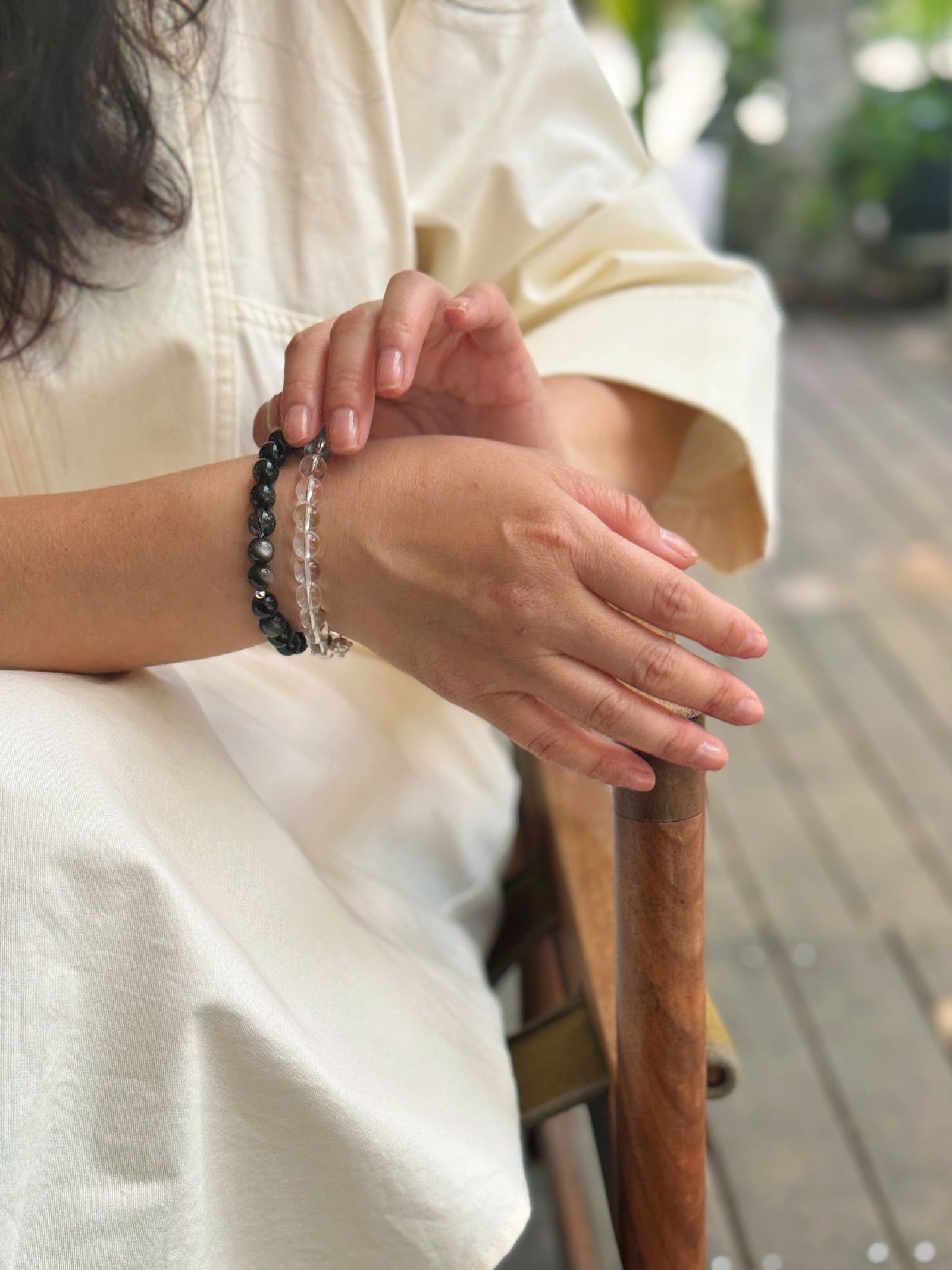 Black obsidian bracelet layered with a clear quartz bracelet in a calm natural lifestyle setting