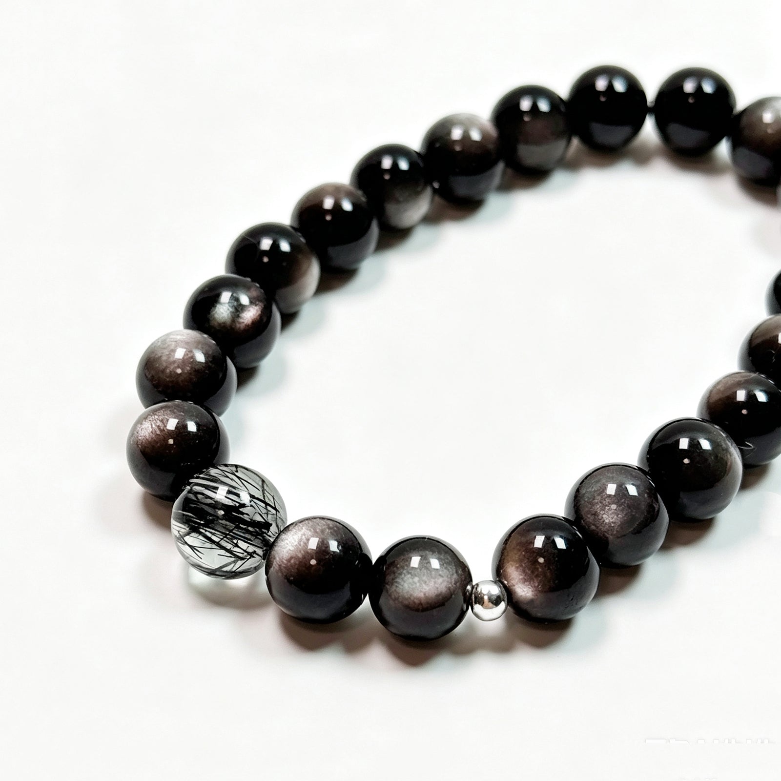 ALT：Close-up detail of black rutilated quartz and black obsidian bracelet showing natural stone texture