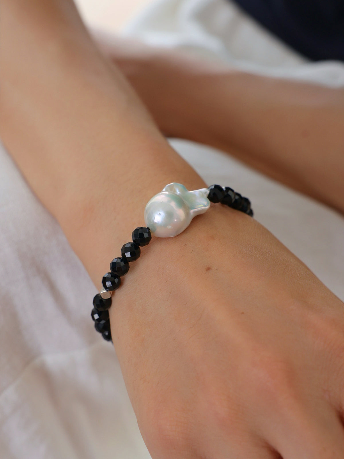 Model wearing a natural Black Spinel and Baroque Freshwater Pearl bracele