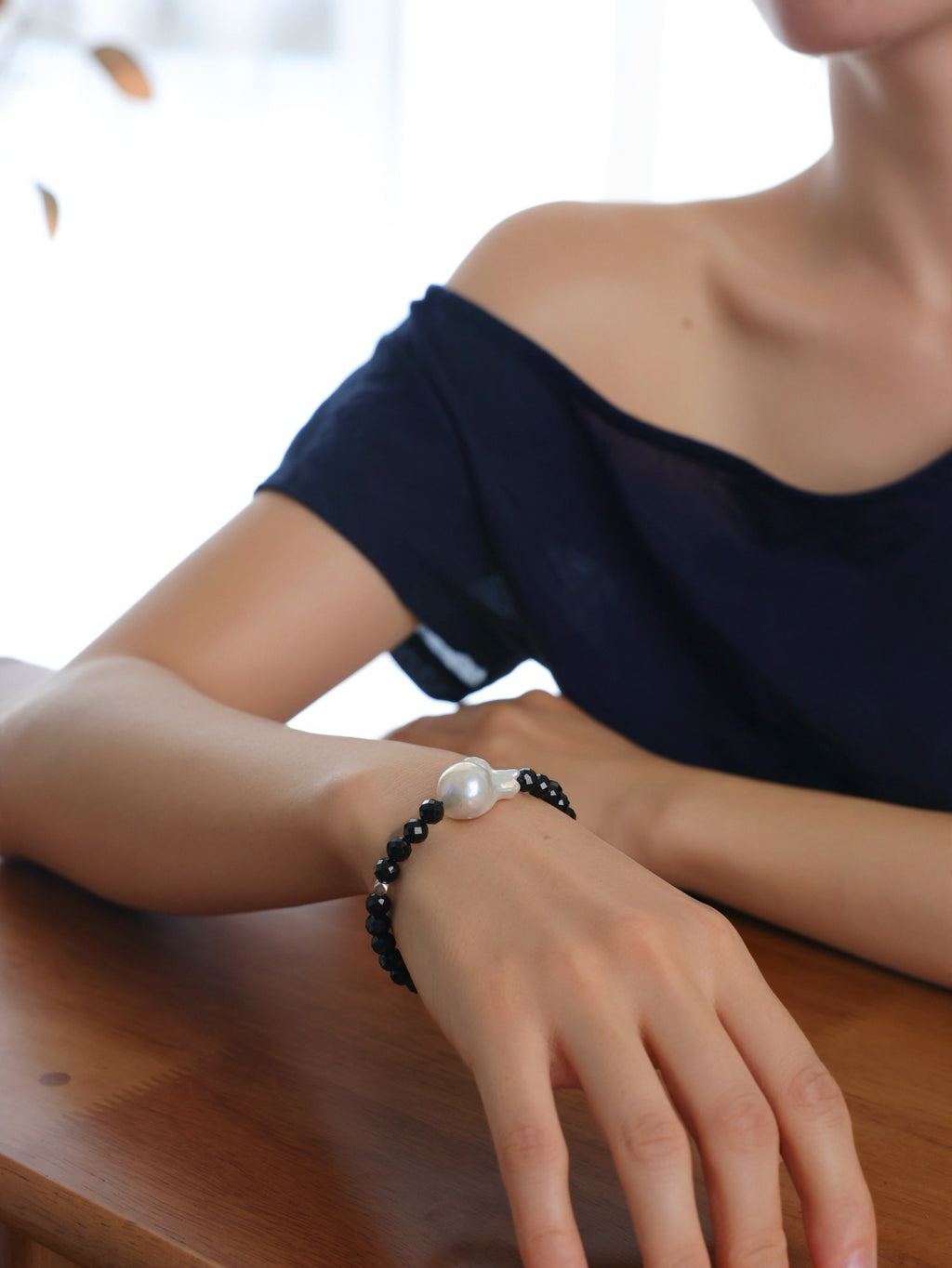 Model wearing a natural Black Spinel and Baroque Freshwater Pearl bracele