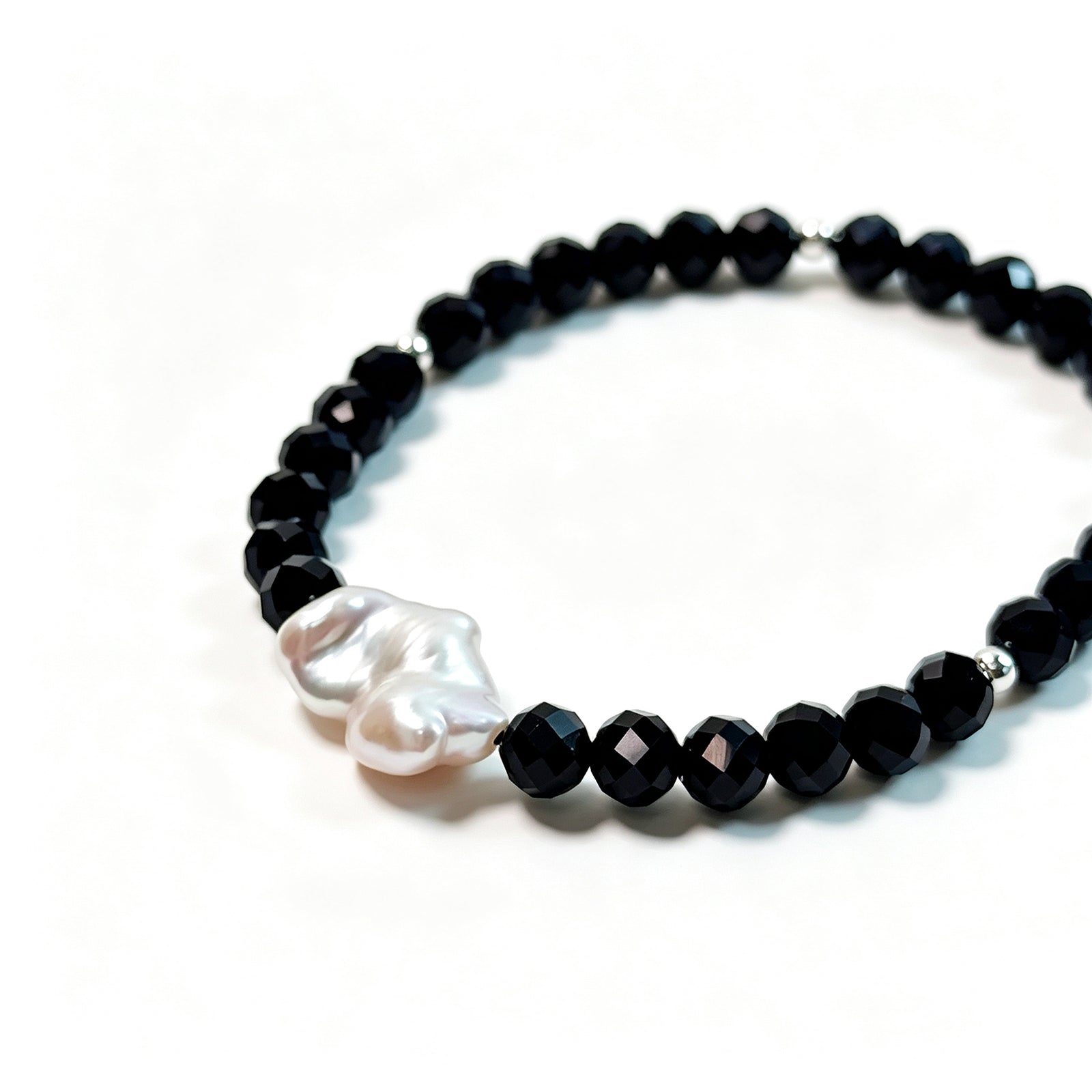 Close-up of black spinel, natural baroque pearl and 925 sterling silver bead bracelet