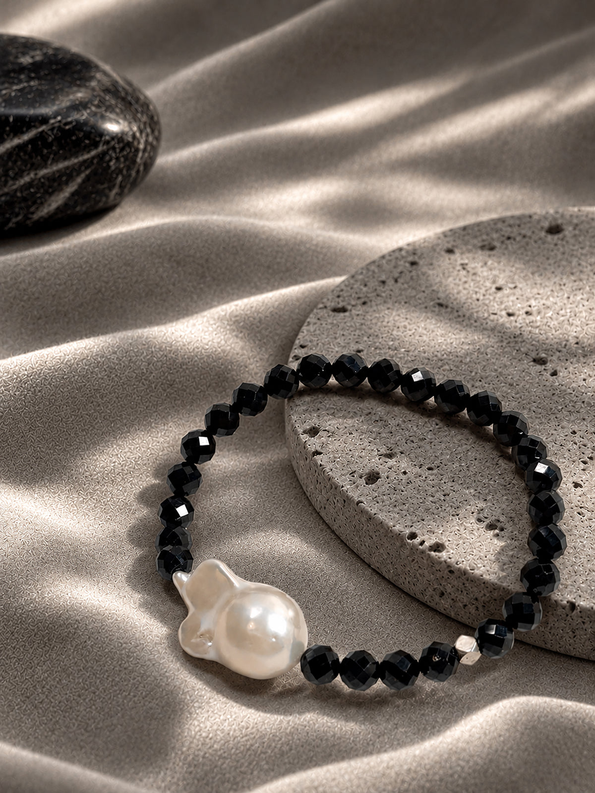 Black spinel and baroque freshwater pearl bracelet in a warm natural setting