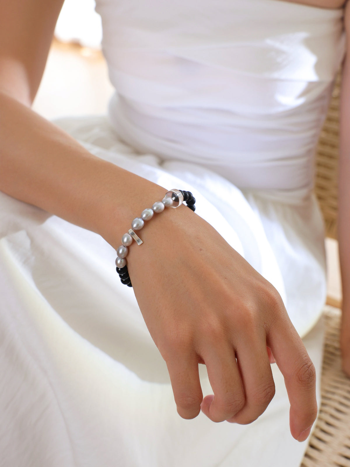 Model wearing a natural Black Tourmaline, Gray Freshwater Pearl and Clear Quartz bracelet with 925 sterling silver accents, featuring a refined minimalist design.