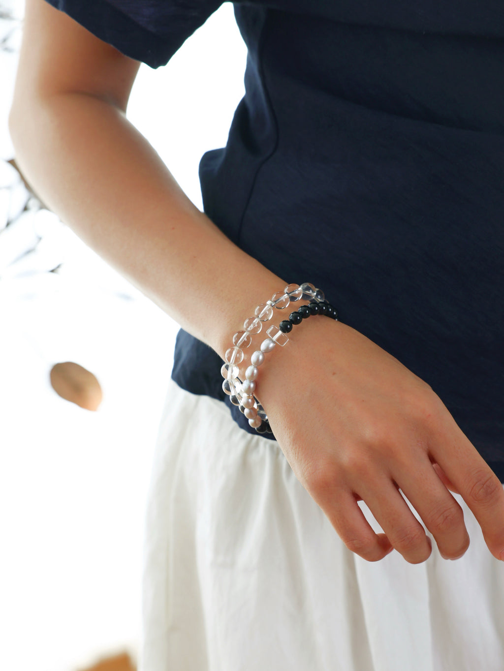 Model wearing a natural Black Tourmaline, Gray Freshwater Pearl and Clear Quartz bracelet with 925 sterling silver accents, featuring a refined minimalist design.