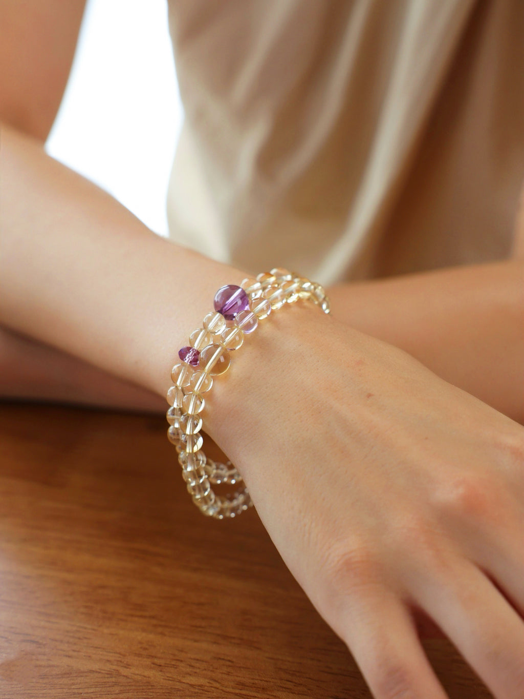 Citrine and amethyst double-wrap bracelet worn on the wrist, highlighting the natural transparency of pale yellow citrine and purple amethyst beads.