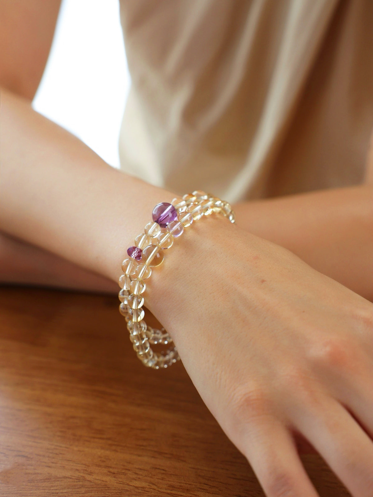 Citrine and amethyst double-wrap bracelet worn on the wrist, highlighting the natural transparency of pale yellow citrine and purple amethyst beads.