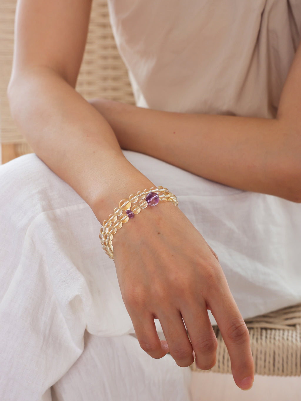 Citrine and amethyst double-wrap bracelet worn on the wrist, highlighting the natural transparency of pale yellow citrine and purple amethyst beads.
