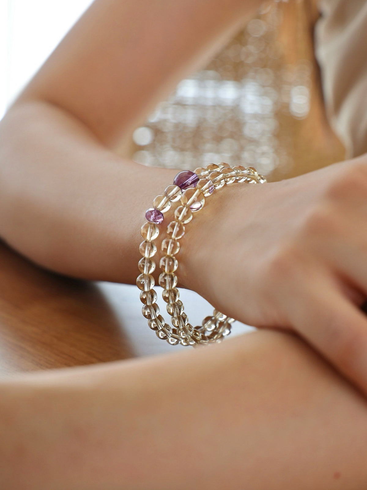 Citrine and amethyst double-wrap bracelet worn on the wrist, highlighting the natural transparency of pale yellow citrine and purple amethyst beads.