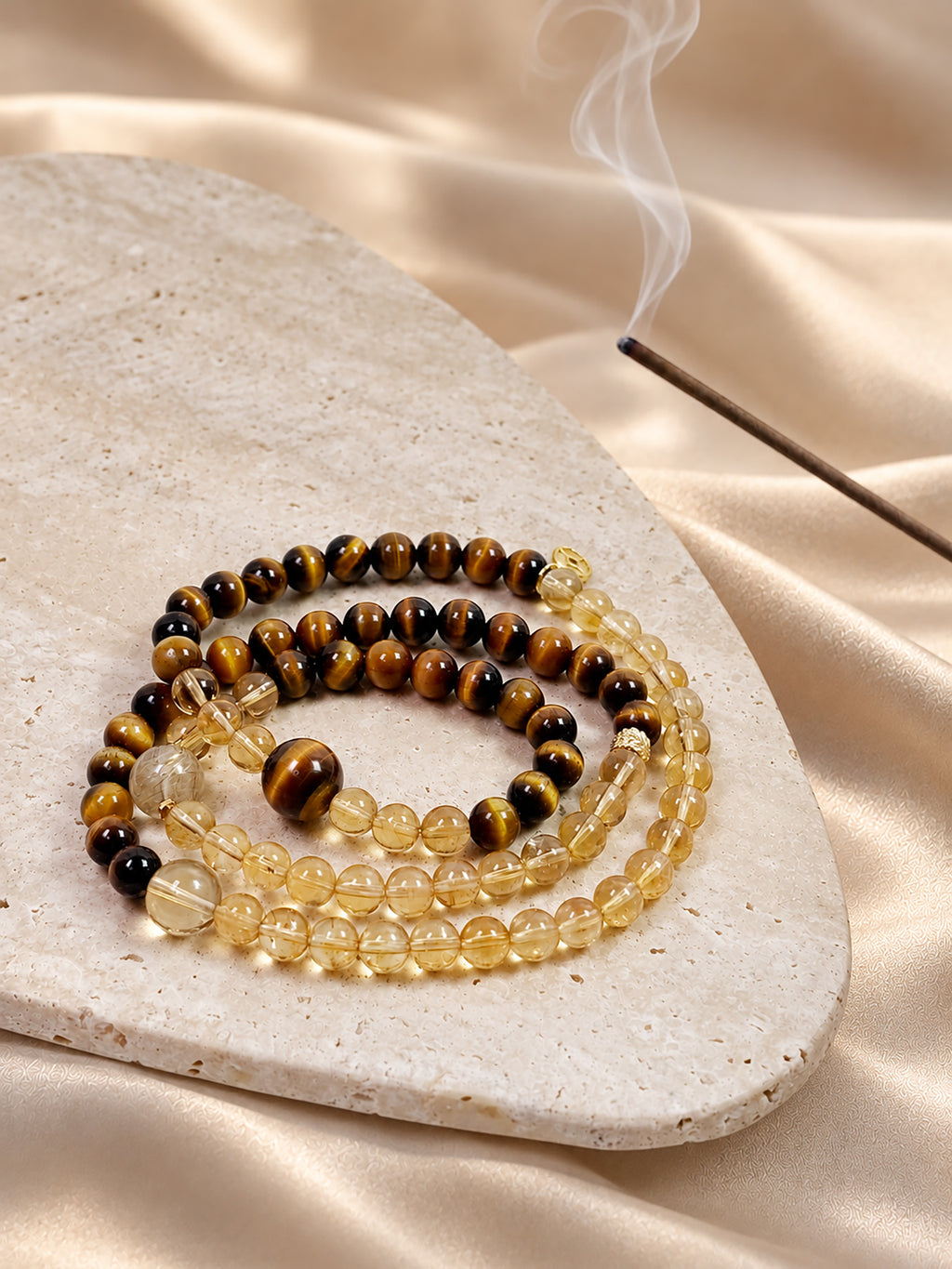 Citrine, Tiger’s Eye and Golden Rutilated Quartz convertible wrap bracelet styled on soft beige satin in a warm, minimalist setting.