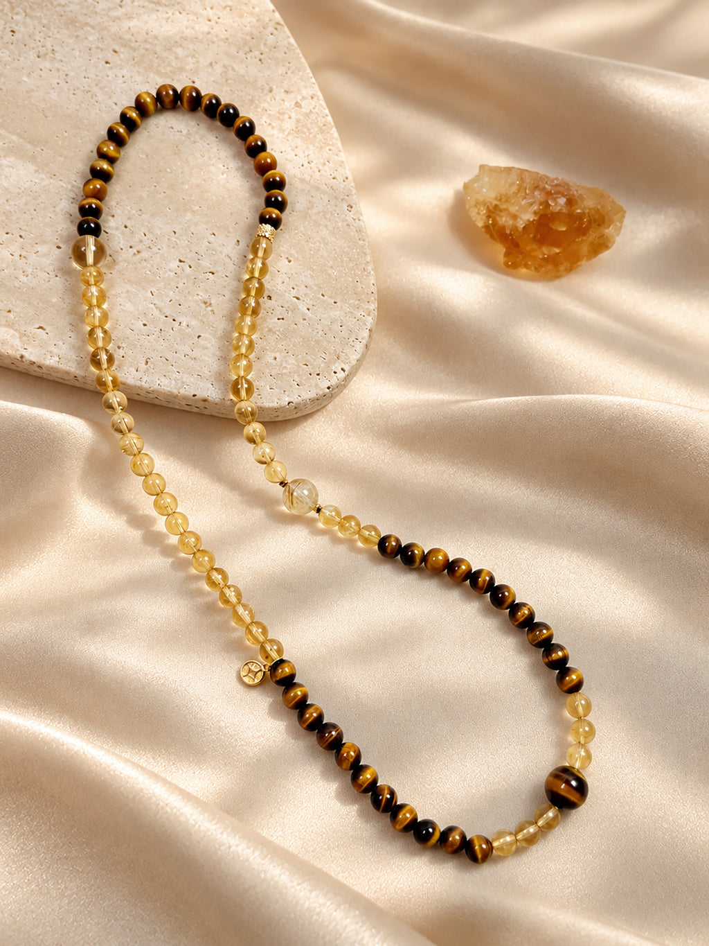 Citrine, Tiger’s Eye and Golden Rutilated Quartz convertible wrap bracelet styled on soft beige satin in a warm, minimalist setting.