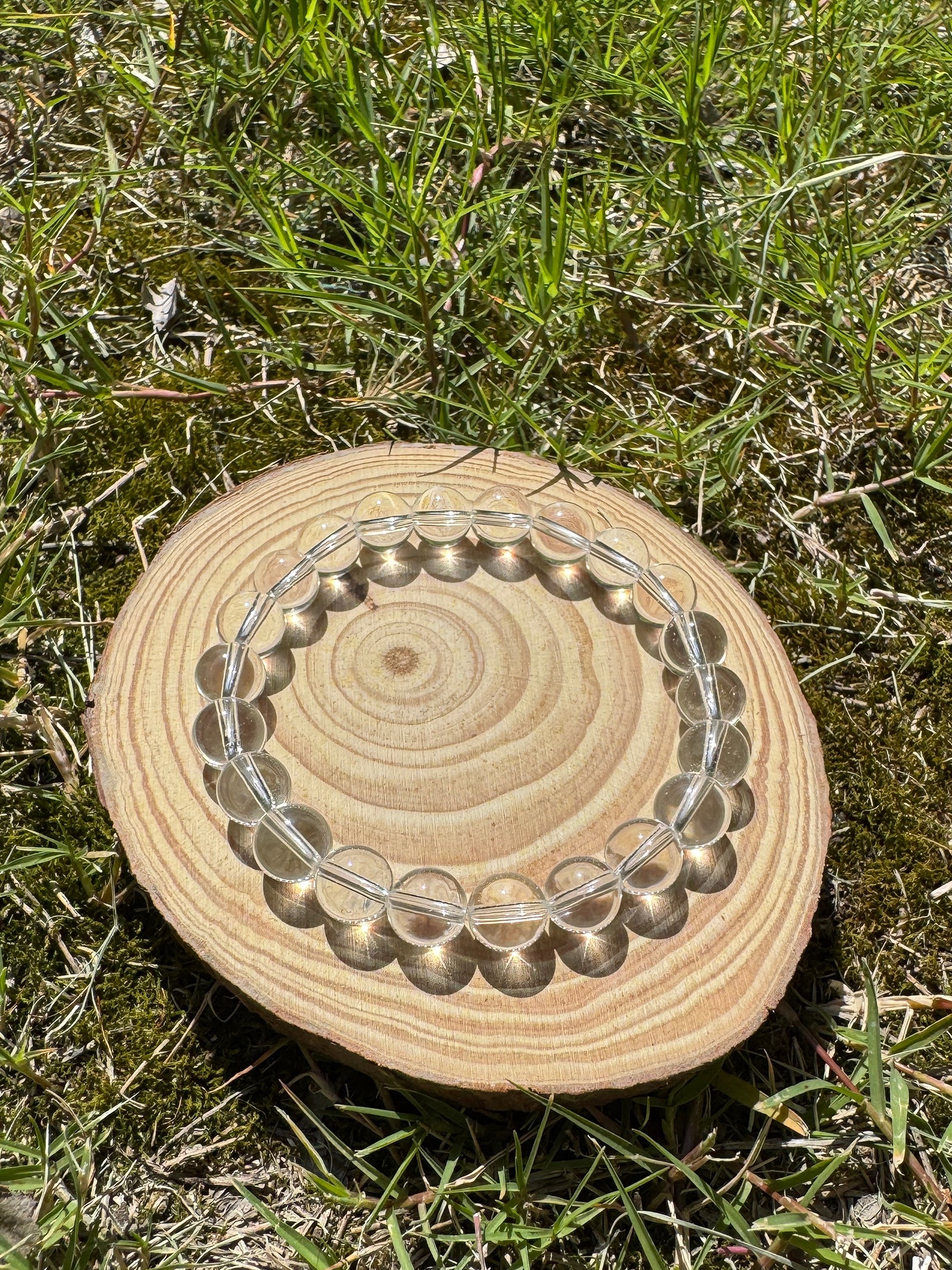 Clear quartz bracelet glowing in natural sunlight on grass