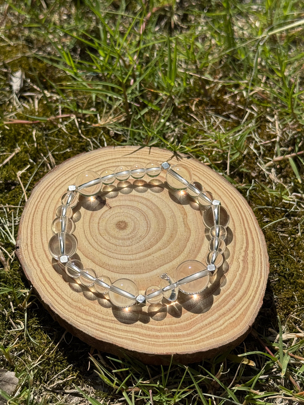 Clear quartz bracelet glowing in natural sunlight on grass
