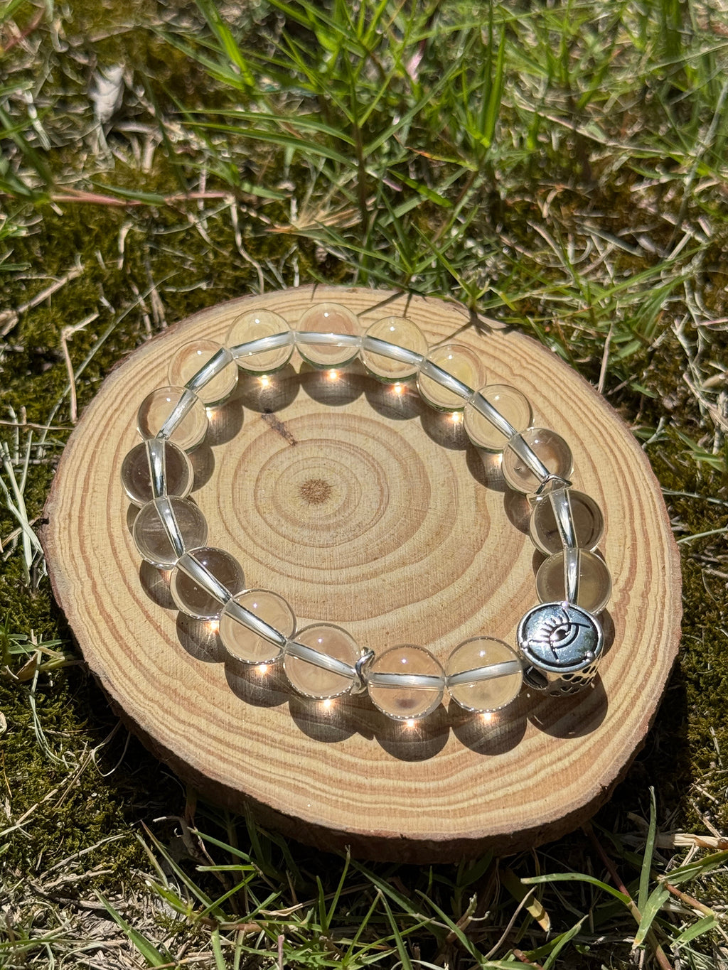 Clear quartz bracelet glowing in natural sunlight on grass