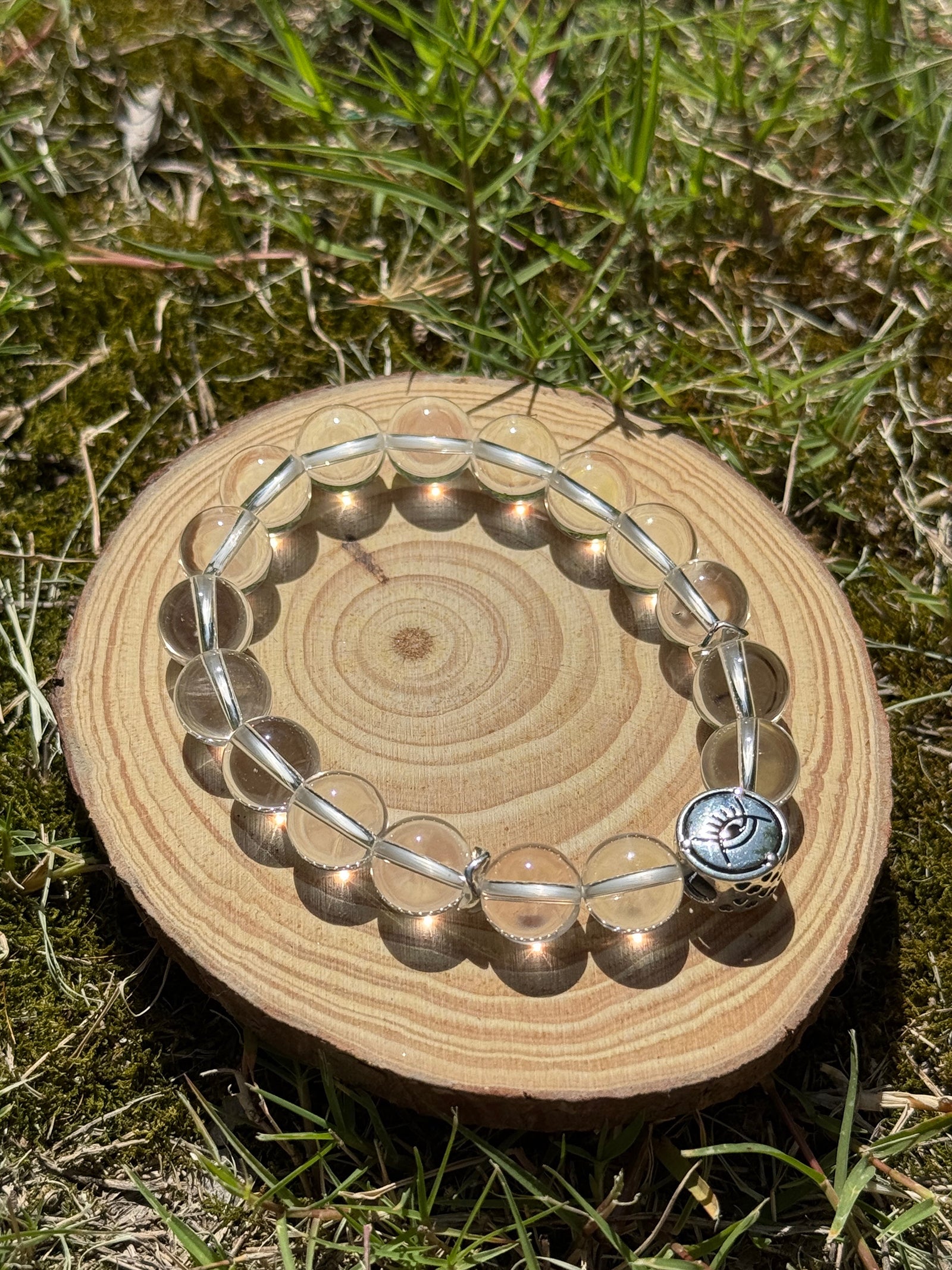 Clear quartz bracelet glowing in natural sunlight on grass