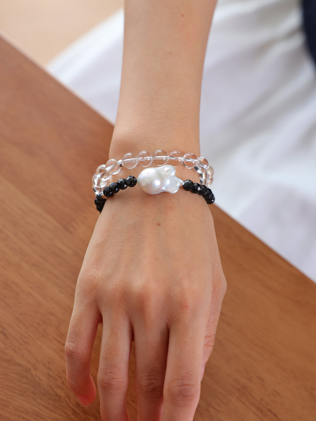 Model wearing a natural Black Spinel and Baroque Freshwater Pearl bracele stacked with a  natural Clear Quartz braceletcrystal bracelets