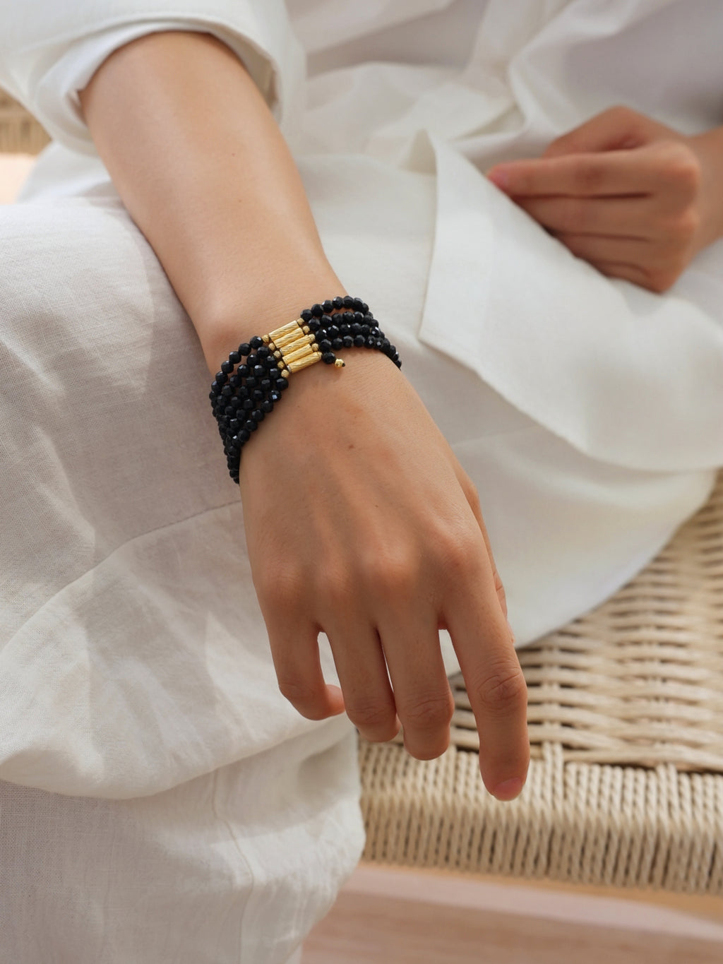 Model wearing a natural undyed faceted Black Spinel multi-wrap bracelet.