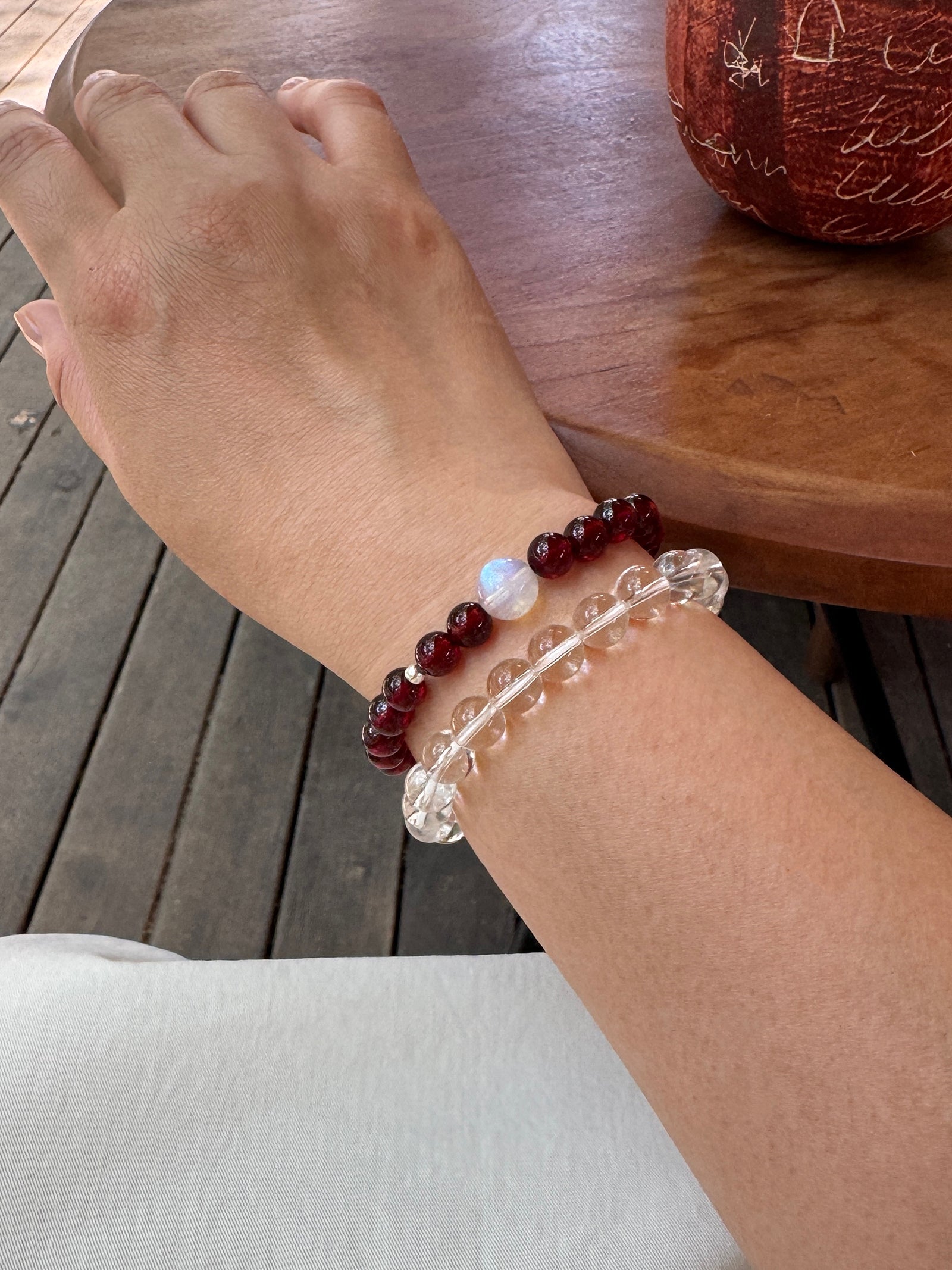 Garnet bracelet layered with clear quartz bracelet close-up on wrist