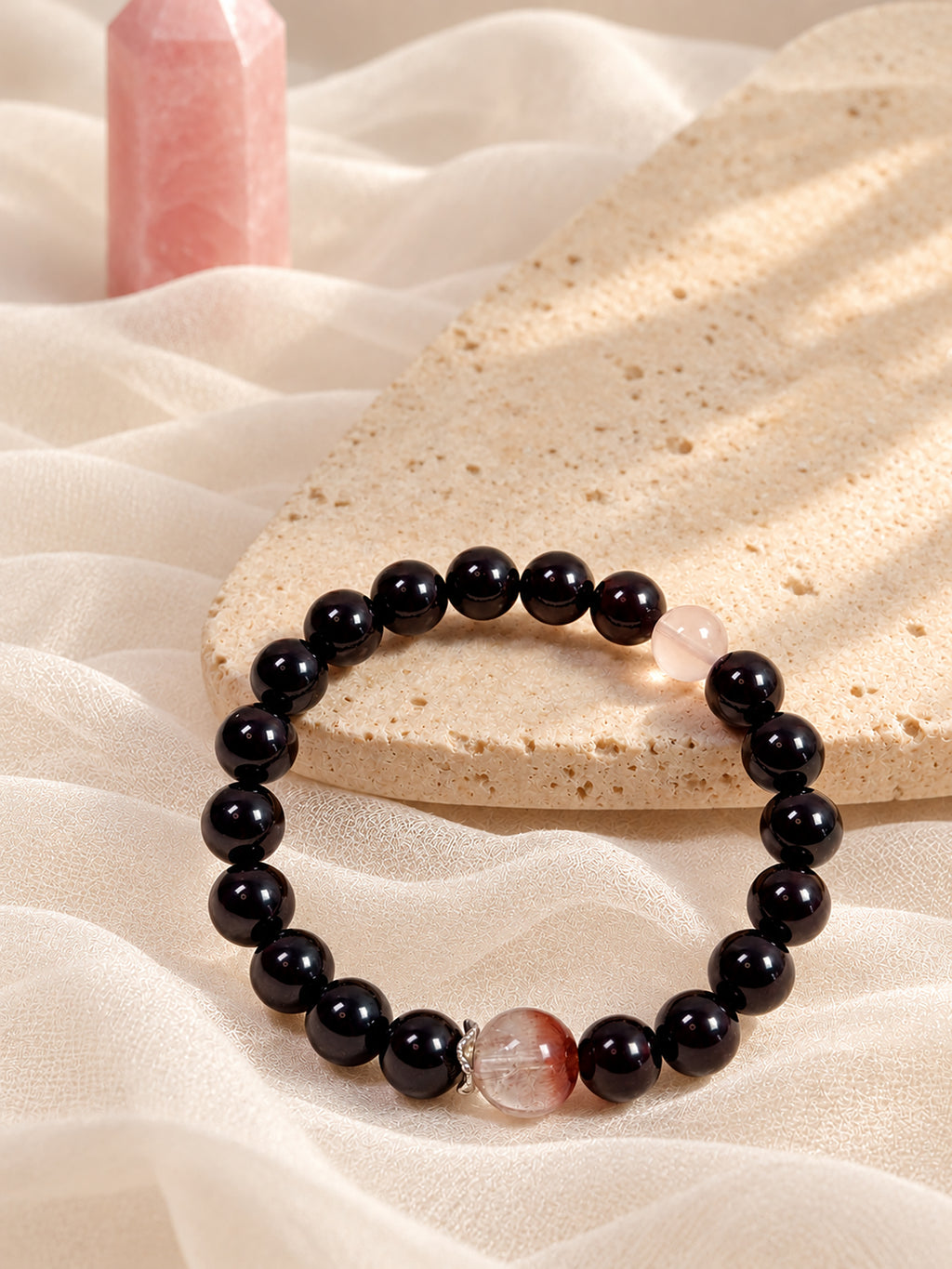 Garnet and pink rabbit hair quartz bracelet styled with natural crystals and soft ambient lighting