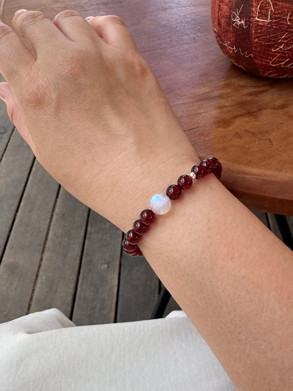 Close-up of garnet and moonstone bracelet worn on wrist showing size and fit
