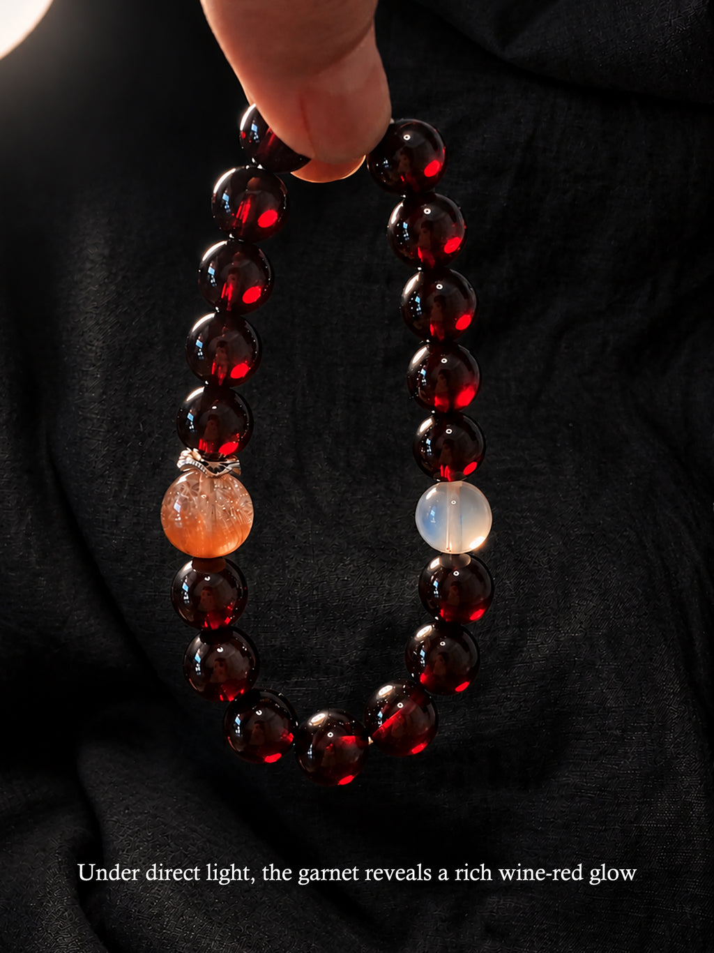 Garnet and Pink Rutilated Quartz crystal bracelet held in warm light, showing the deep wine-red clarity of natural Garnet beads.