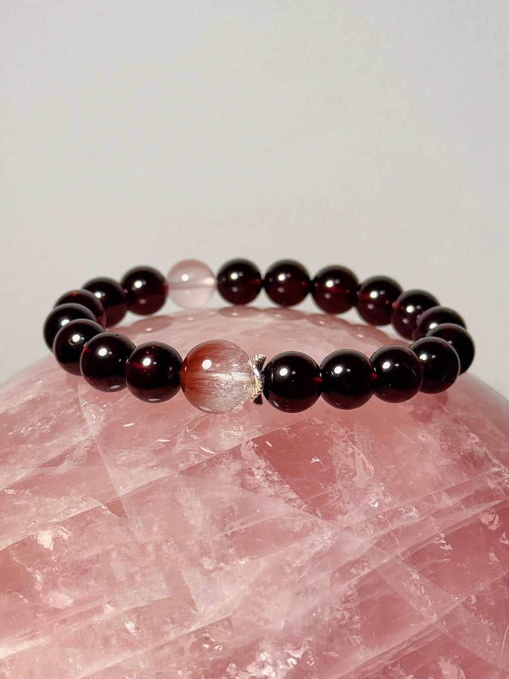 
Garnet rose quartz and pink rabbit hair quartz bracelet in artistic still life composition