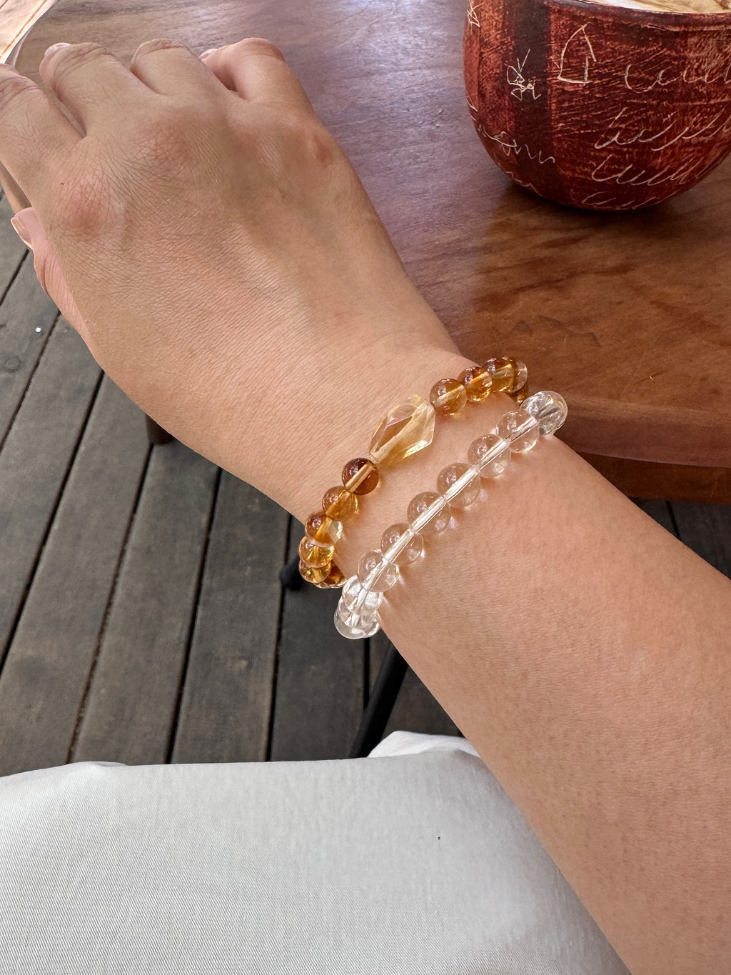 Golden healer quartz bracelet layered with clear quartz bracelet close-up on wrist