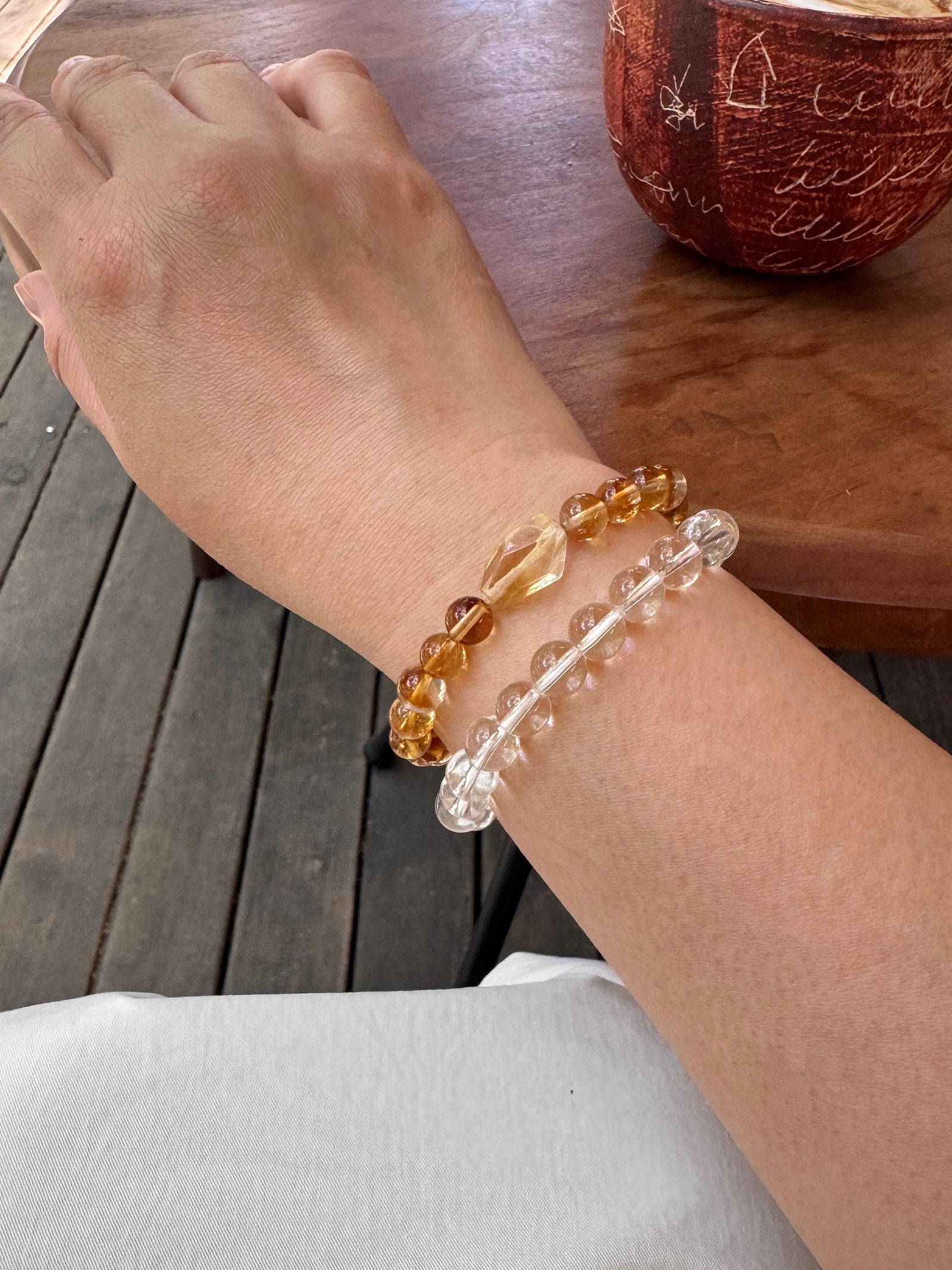 Golden healer quartz bracelet layered with clear quartz bracelet close-up on wrist