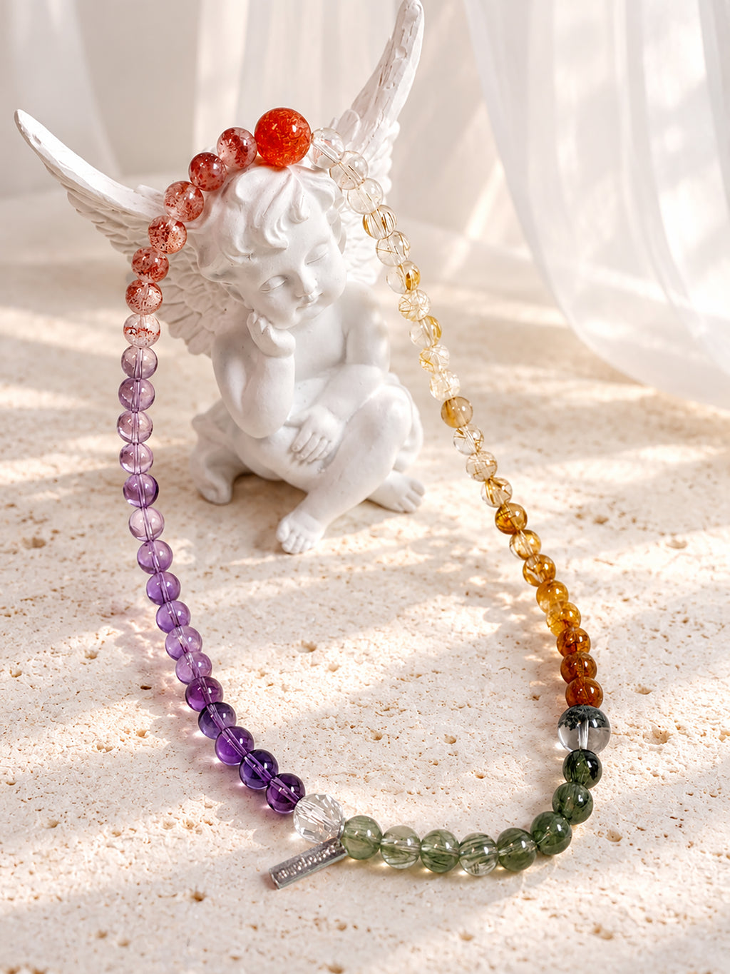 Artistic product photography of Four Seasons in Miniature bracelet featuring Golden Strawberry Quartz, Golden Sunstone, Citrine, Golden Rutilated Quartz, Copper Rutilated Quartz, Green Phantom Quartz, Green Rutilated Quartz, Amethyst, and Clear Quartz.
