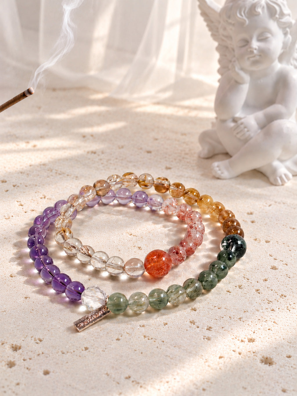 Artistic product photography of Four Seasons in Miniature bracelet featuring Golden Strawberry Quartz, Golden Sunstone, Citrine, Golden Rutilated Quartz, Copper Rutilated Quartz, Green Phantom Quartz, Green Rutilated Quartz, Amethyst, and Clear Quartz.
