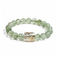 Green rutilated quartz bracelet with natural scenic stone charm on white background