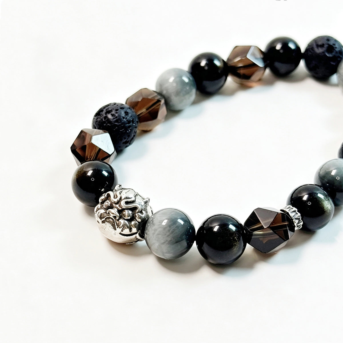 Close-up of Obsidian, Smoky Quartz, Hawk’s Eye and Lava Stone bracelet with 925 sterling silver guardian face charm

