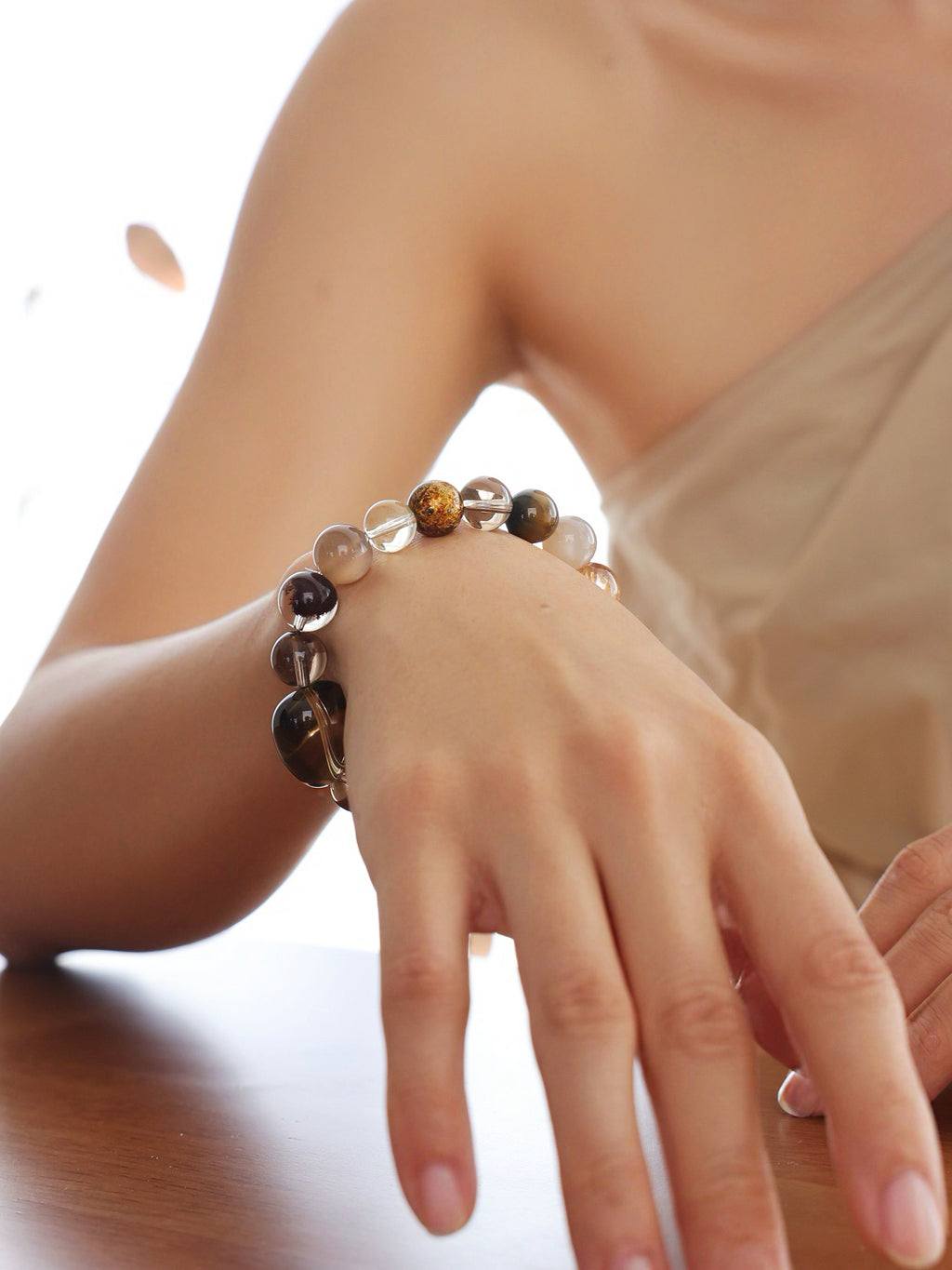 Model wearing a natural Smoky Quartz, Phantom Quartz and Copper Rutilated Quartz Bracelet, showing its gemstone proportions and fit on the wrist.