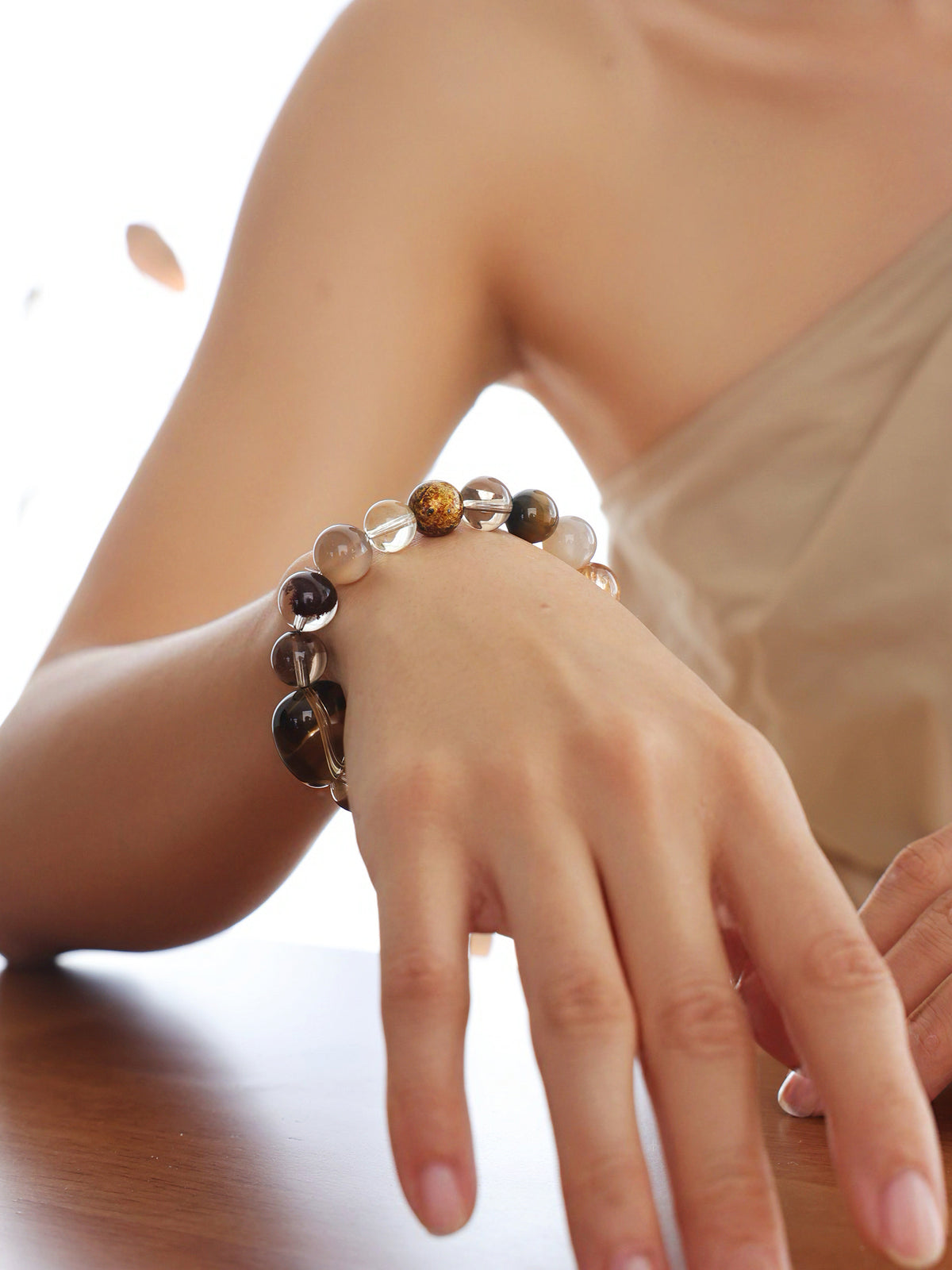 Model wearing a natural Smoky Quartz, Phantom Quartz and Copper Rutilated Quartz Bracelet, showing its gemstone proportions and fit on the wrist.