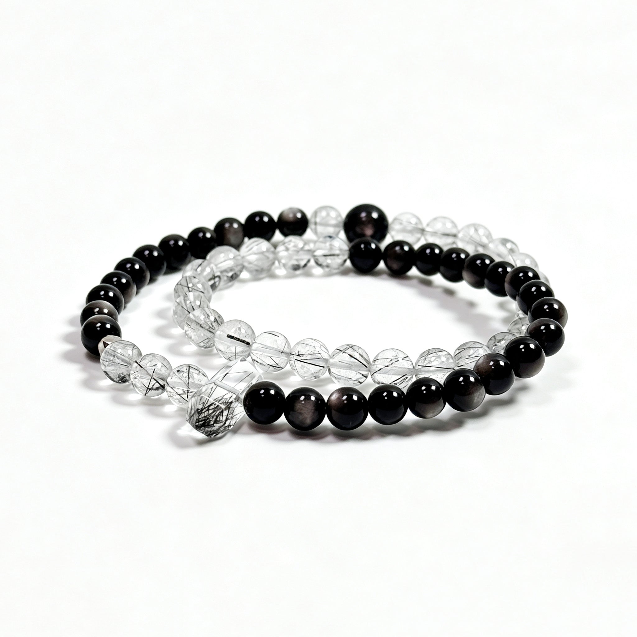 Black rutilated quartz and obsidian bracelet on clean white background for protection and stability