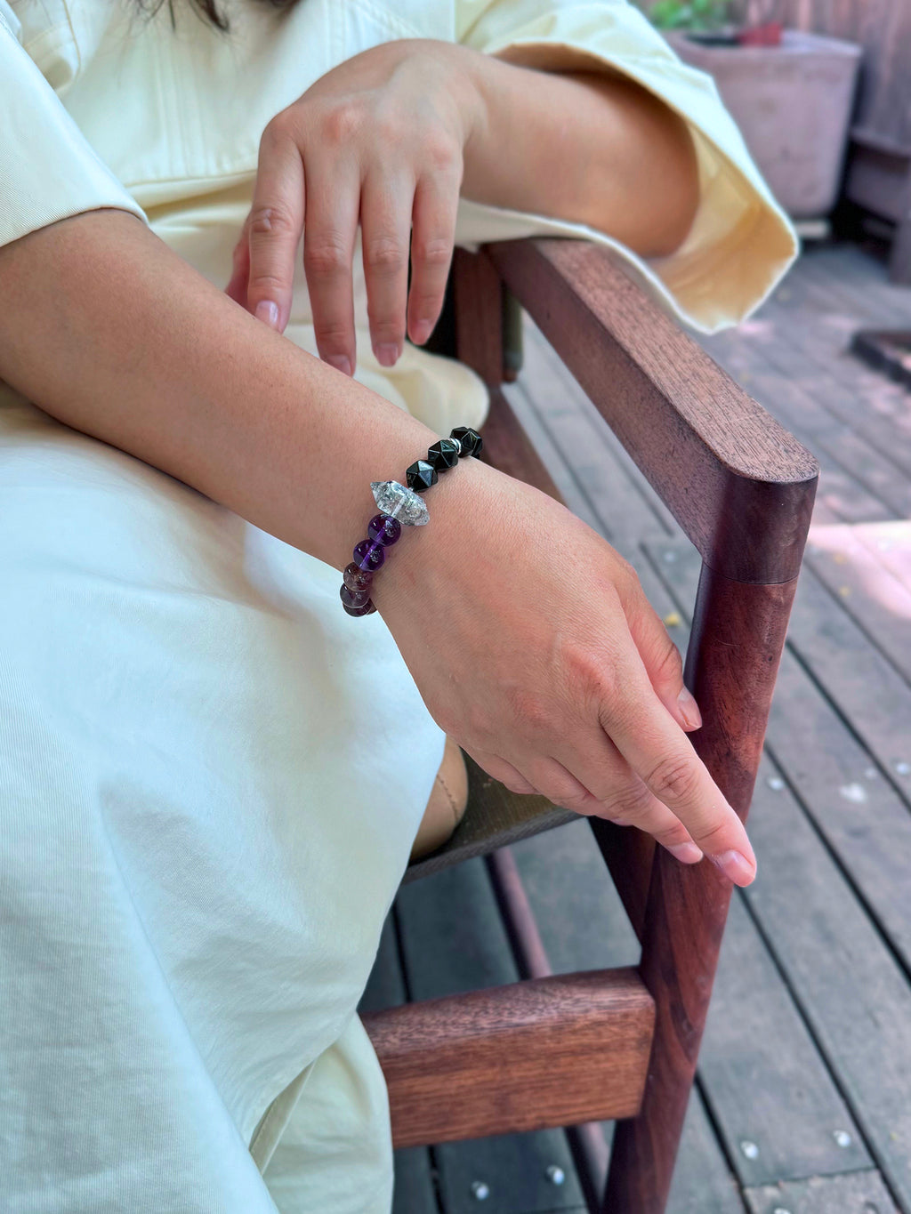 Purple titanium quartz, amethyst, and obsidian bracelet worn in a calm lifestyle setting for energetic boundaries and emotional stability