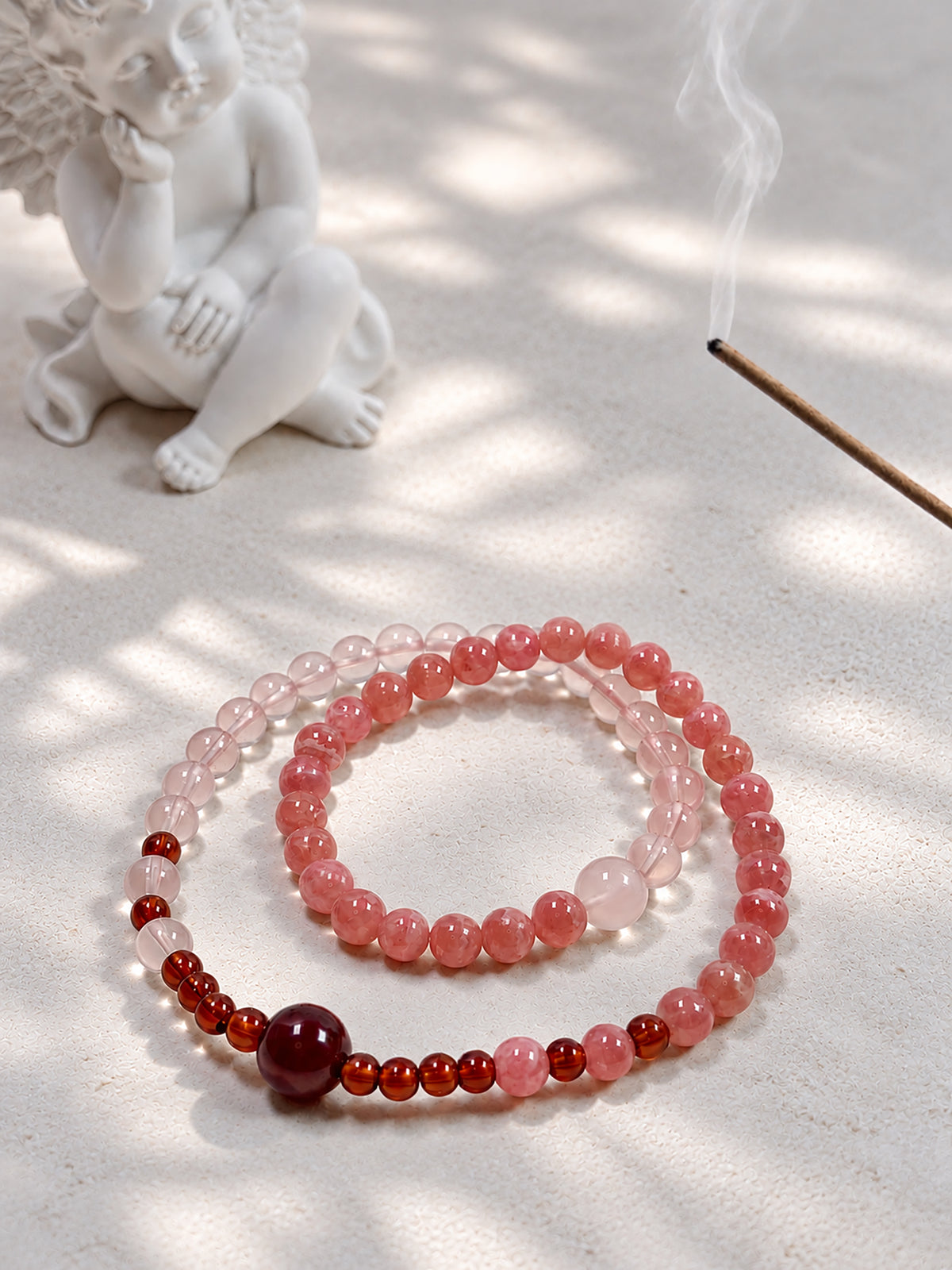 Double-wrap crystal bracelet featuring translucent Rhodochrosite, luminous Star Rose Quartz, and Orange-Red Garnet in a refined setting.