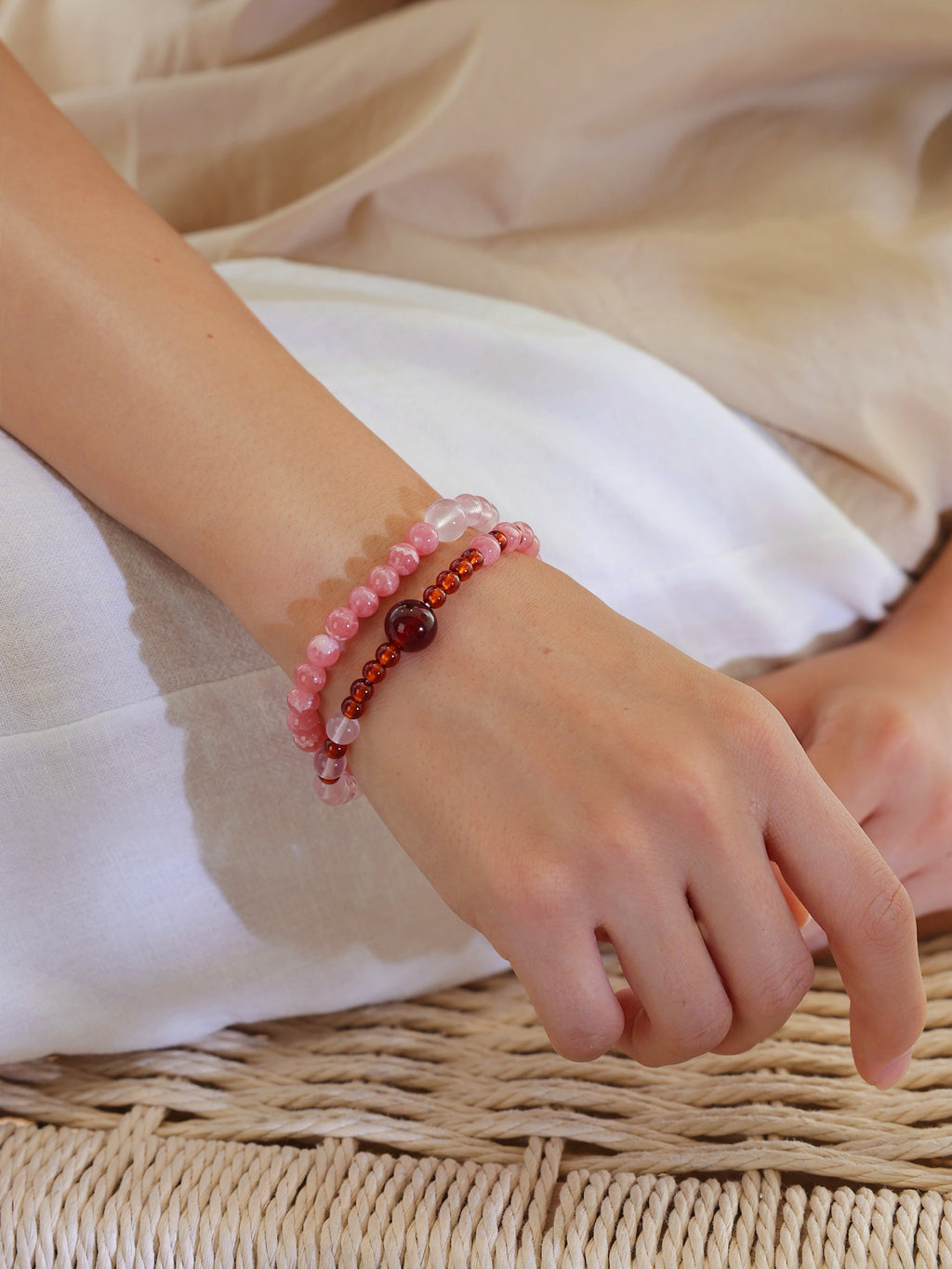 Close view of a double-wrap Rhodochrosite, Star Rose Quartz, and Orange-Red Garnet bracelet worn on the wrist.