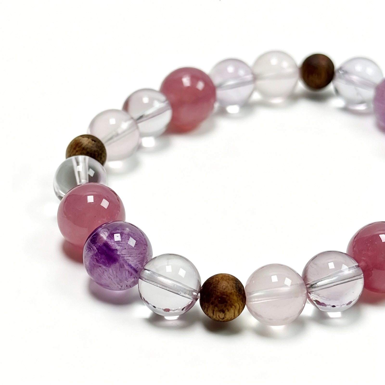Close-up detail of rose quartz, Super Seven, and agarwood bracelet showing natural crystal texture and layered bead composition