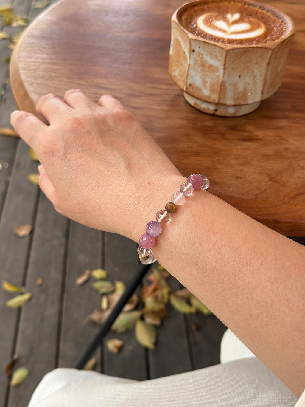 Close-up of rose quartz and Super Seven bracelet worn on wrist showing natural crystal textures and soft layered tones
