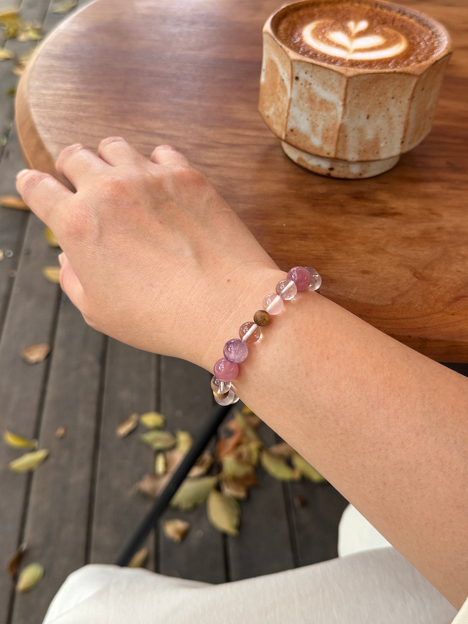 Close-up of rose quartz and Super Seven bracelet worn on wrist showing natural crystal textures and soft layered tones
