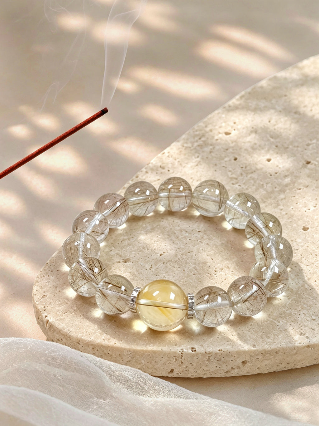 Silver Rutilated Quartz manifestation bracelet styled on meditation altar with calming spiritual objects