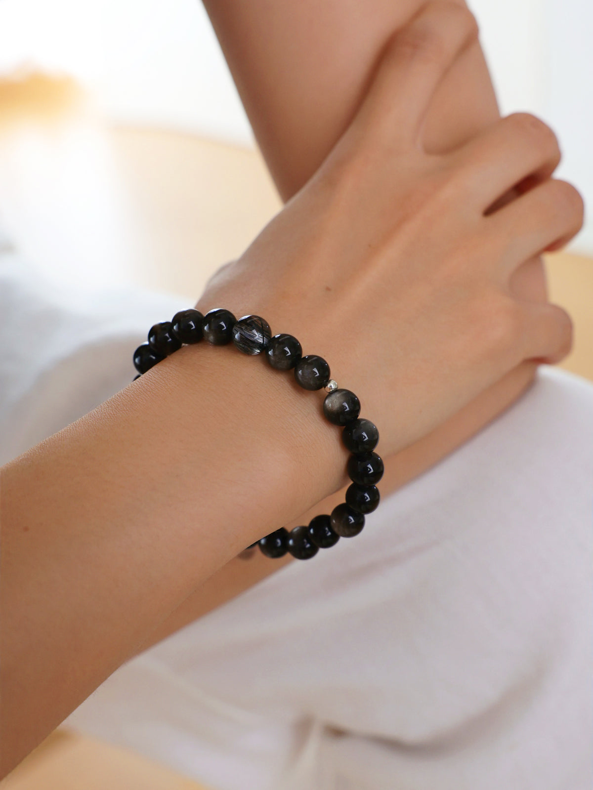Model wearing a natural Silver Sheen Obsidian and Clear Black Rutilated Quartz bracelet