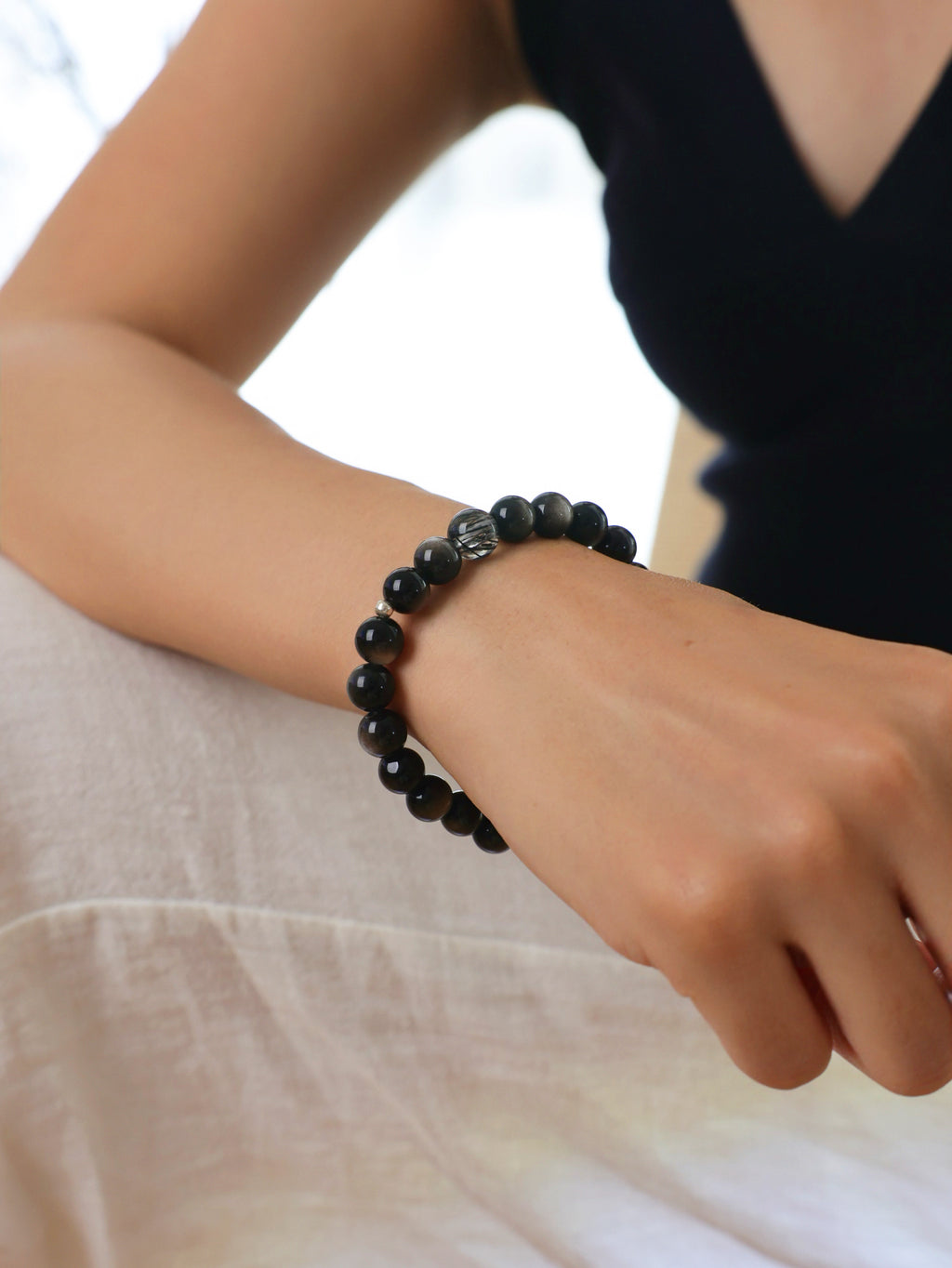 Model wearing a natural Silver Sheen Obsidian and Clear Black Rutilated Quartz bracelet