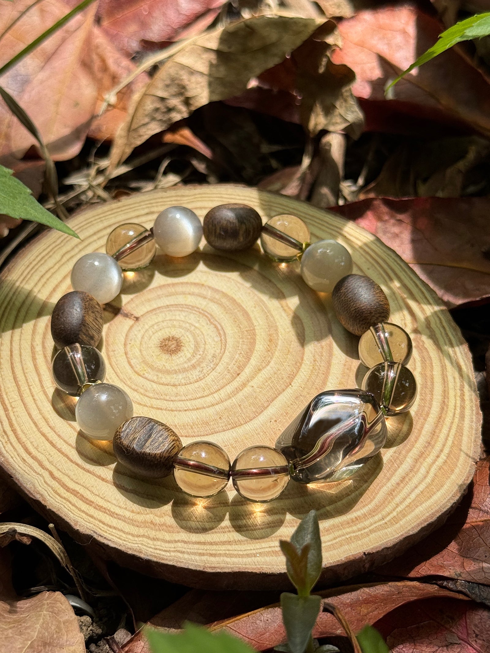 Natural smoky quartz and agarwood bracelet resting on sunlit grass