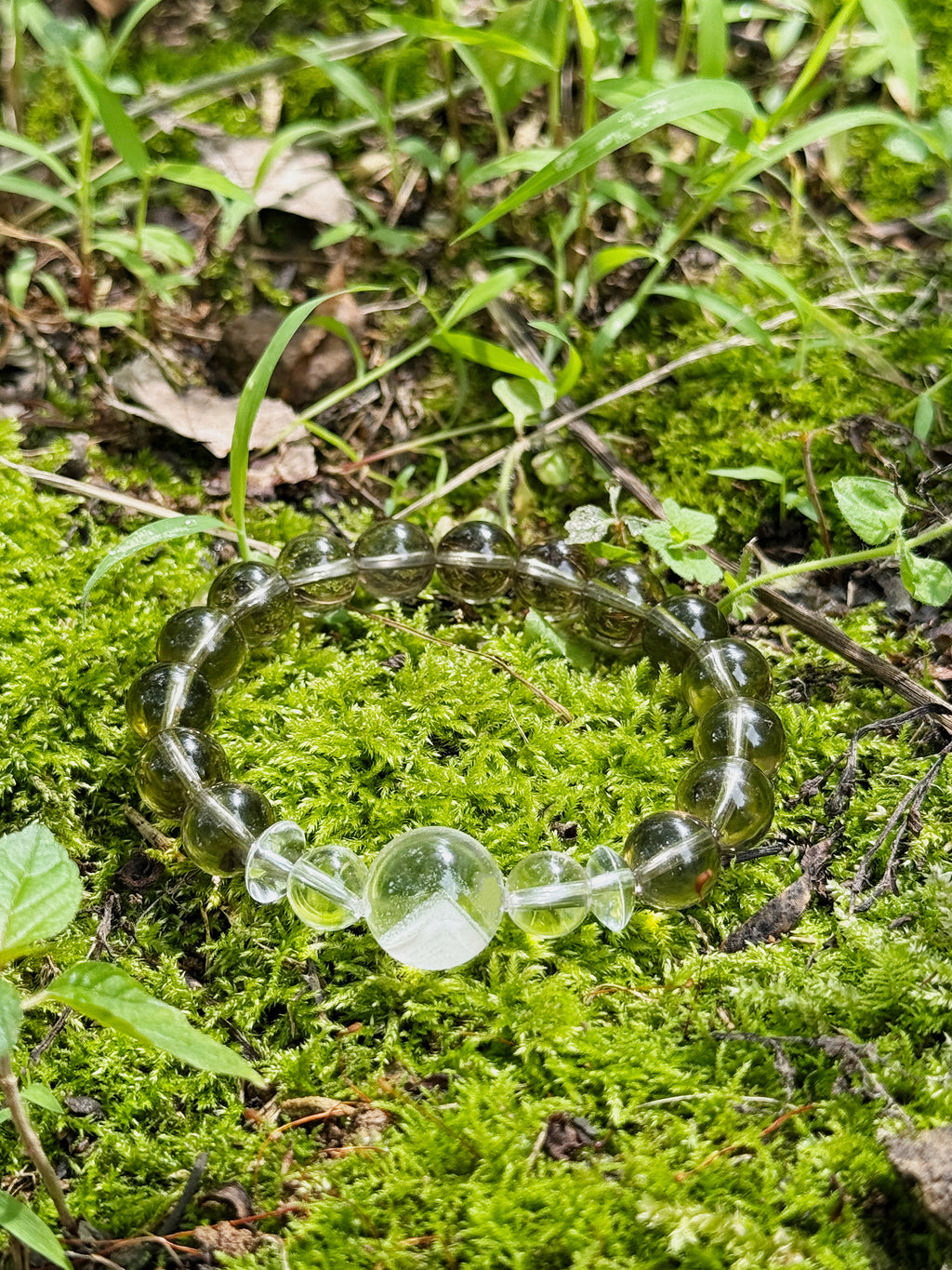 moky quartz bracelet with white phantom quartz focal bead photographed on moss in natural light