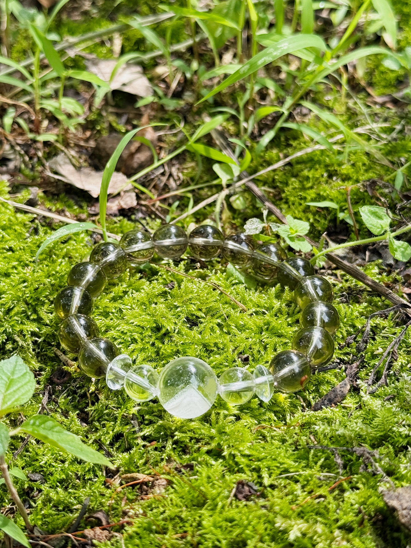 moky quartz bracelet with white phantom quartz focal bead photographed on moss in natural light