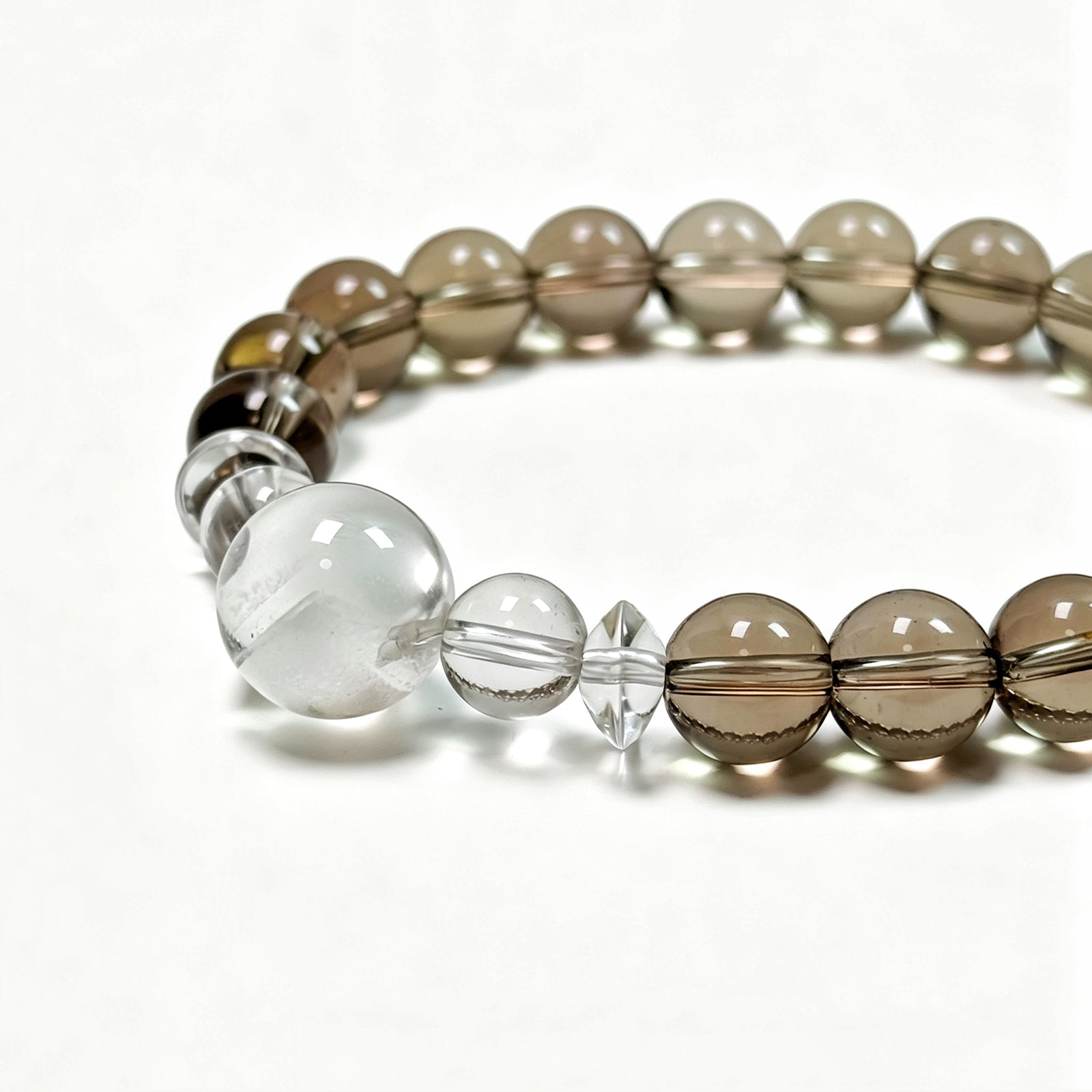 Close-up detail of white phantom quartz focal bead and smoky quartz bracelet showing natural crystal texture